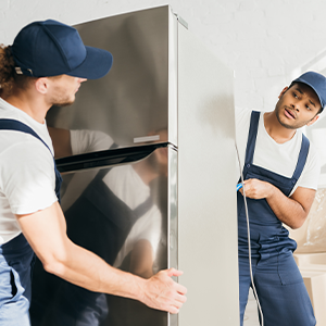 Two people moving an appliance.