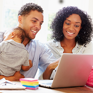 A family of three smiling and browsing online together.